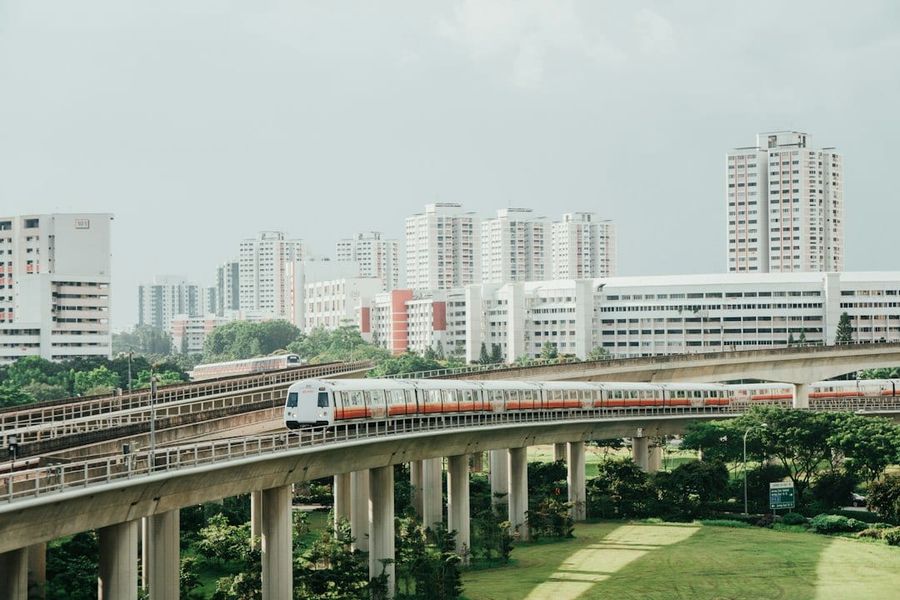 Red and white train on rail near city buildings during daytime